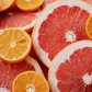 A collection of sliced and whole oranges and grapefruits with a lemongrass background.