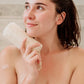 women looking into the distace holding a long loofah 