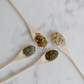 four wooden spoons filled with different types of essential oils, placed on a marble surface.